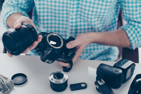 Cropped close up non face portrait of man assemble camera after repair expertising having lens flash small details on the table Stock Photo