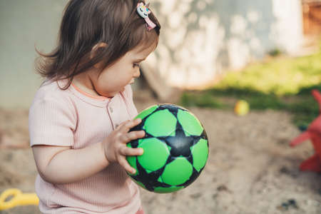 Retrato de niña sosteniendo un balón de fútbol de juguete y listo para lanzarlo. desarrollo del bebé. niño activo jugando al aire libre.