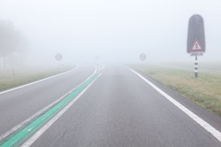 On a foggy road along nature with a limited view