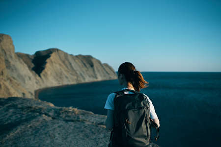 Woman with backpack in the mountains in nature back view