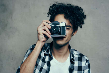 Facet z aparatem w dłoniach na szarym tle w domu model koszuli w kratę hobby Zdjęcie Seryjne