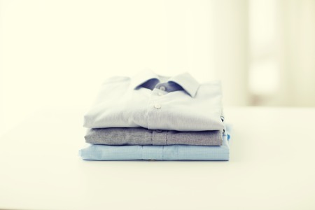 Ironing laundry clothes housekeeping and objects concept close up of ironed and folded shirts on table at home