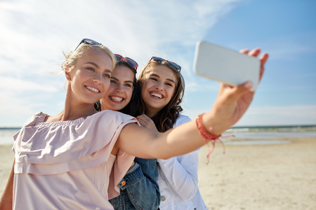 vacaciones, viajes, tecnología verano y la gente concepto-grupo de la sonrisa jóvenes que toman el sulfuro con smartphone en la playa - 63316294