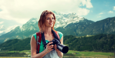 Adventure travel tourism hike and people concept happy young woman with backpack and camera photographing over alps mountains background