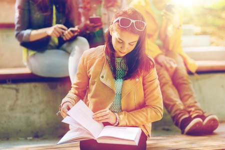 High school student girl reading book outdoors