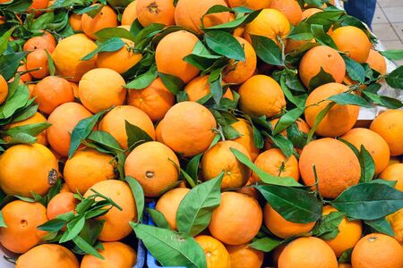 Pile of oranges with leaves for sale at a market Stock Photo