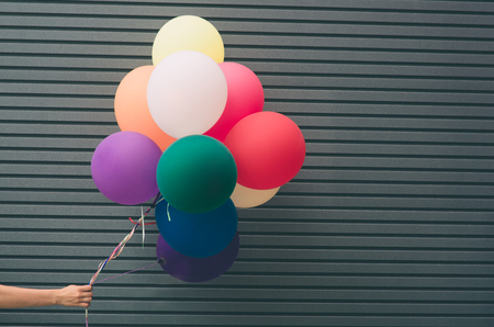 Multicolored latex balloons filled with helium near the gray wall festive concept with a place for your text