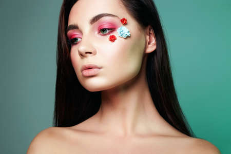 Sensual beautiful girl with flowers on the face beauty make up woman with pink eye shadow