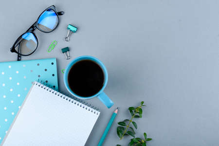 Blue notebook with a blue pencil on a gray background phone glasses and a cup of coffee office