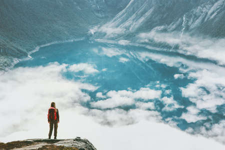 Traveling woman above clouds and lake in mountains adventure lifestyle wanderlust concept vacations outdoor hiking with backpack