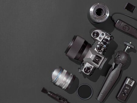 Photographer workplace with dslr camera lens pen tablet and camera accessories on black background camera photography visual content concept flat lay or top view copy space hard light