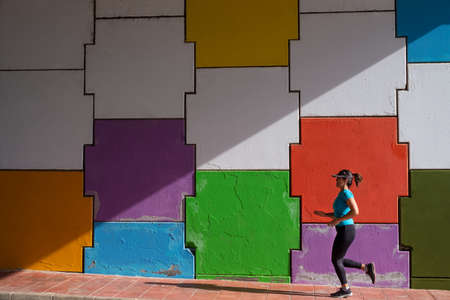 Mujer corriendo frente a un fondo multicolor