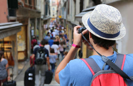 joven fotógrafo con sombrero toma algunas fotos de una ciudad con gente