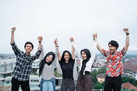 Young people hanging out and raise hand on the building rooftop