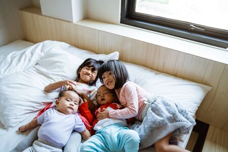 cuatro niños felices de jugar y bromear en la cama