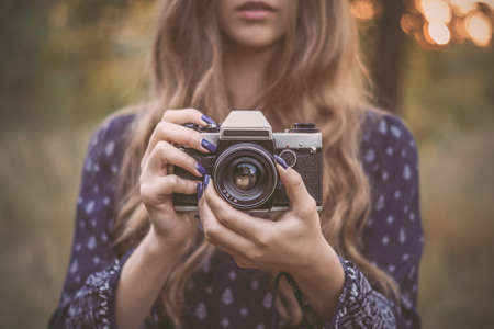 Pretty girl with vintage camera in park