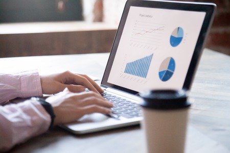 Close up of womans hands working on laptop graph chart and diagram on pc screen statistics of sales market research concept