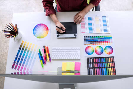 Image of female creative graphic designer working on color selection and drawing on graphics tablet at workplace top view workspace