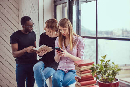 Group of young multiracial students working with books and phone Stock Photo