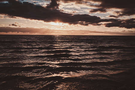 Hermosa puesta de sol colorida en la playa con algunas nubes y reflejo dorado en el agua. Foto de archivo