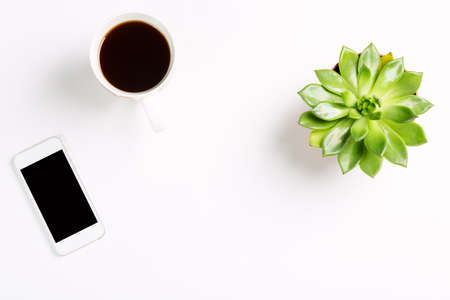 Top view of empty office desk green plant in a pot with cup of coffee and modern mobile phone and on white background copy space for your text