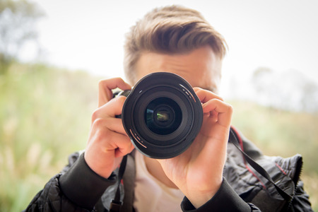 Young blonde man shooting photos