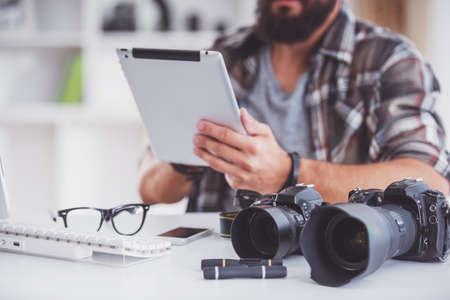 Young cheerful photographer with beard while working in his office