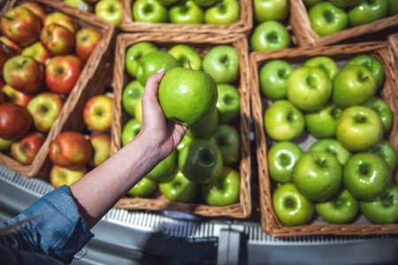 At the supermarket fresh fruits waiting for customers woman s hand holding an apple Stock Photo