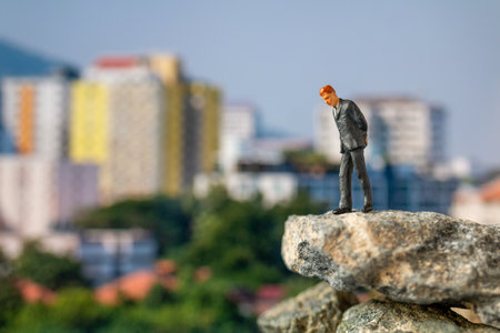 Miniature people, Businessman staande op de rots met bouwachtergrond Stockfoto