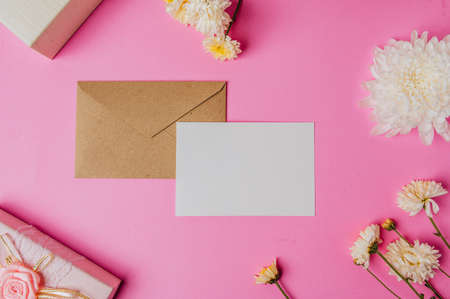 Caja de regalo rosa sobre marrón con tarjeta en blanco y flor sobre fondo rosa