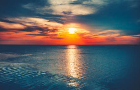 Fondo de cielo al atardecer. Puesta del sol natural Salida del sol sobre el océano. Brillante cielo dramático y agua azul. Paisaje colorido de la naturaleza