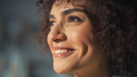 Primer plano retrato de una morena multiétnica con cabello rizado y ojos marrones feliz y creativa joven sonriendo encantadoramente y sintiéndose alegre pensando en ideas sobre un futuro mejor