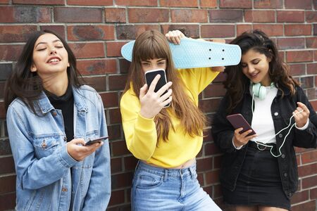 Three young women having fun with mobile phone Stock Photo