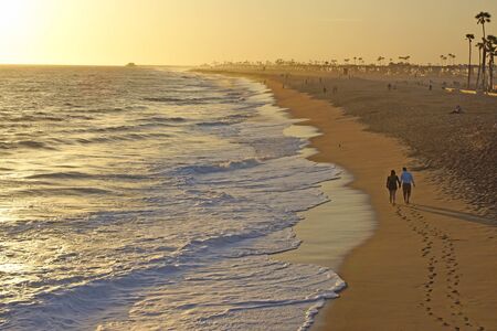 Pareja caminando en la arena en la playa de California durante el atardecer