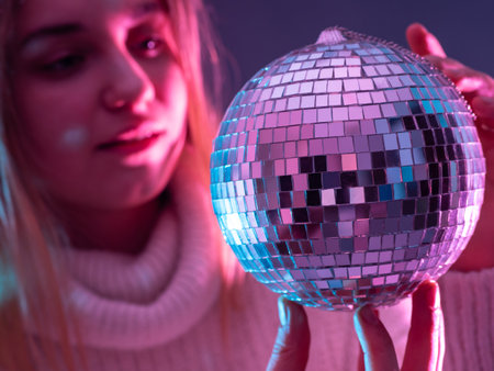 Disco ball on the background of a blurry female face mirror ball glows in the dark the girl admires the mirror ball romantic mood romantic girl with mirrow decoration