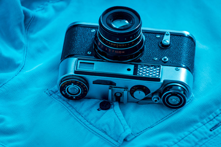 Retro styled camera close up of retro camera laying on blue shirt