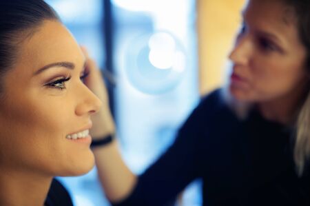 Makeup artist applying liquid tonal foundation on the face of the woman