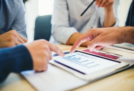 Group of businesspeople with tablet working together in office midsection