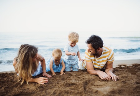 Una familia con dos niños pequeños en la playa de arena en vacaciones de verano.