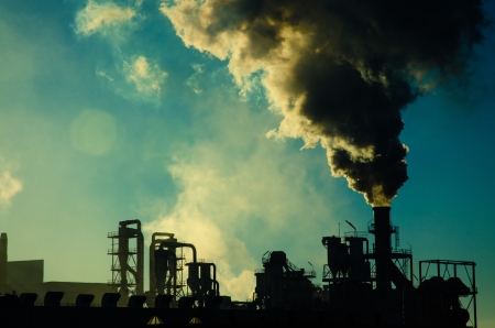 Smoking chimney at sunset on industrial buildings complex Stock Photo