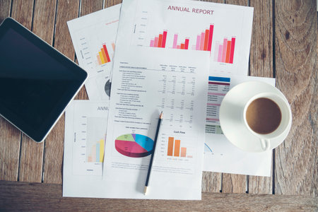 Office laptop business financial document chart and graph on wooden table with coffee cup flat lay notebook computer laptop on office desk no people business graph chart mockup on business workspace