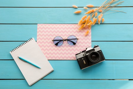 Vista superior de cerca del cuaderno de dibujo con bolígrafo azul, gafas de sol ubicando cerca de la cámara Foto de archivo