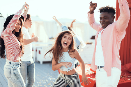 Satisfied girls and cheerful men dancing during positive party outside glad comrades during entertainment concept Stock Photo