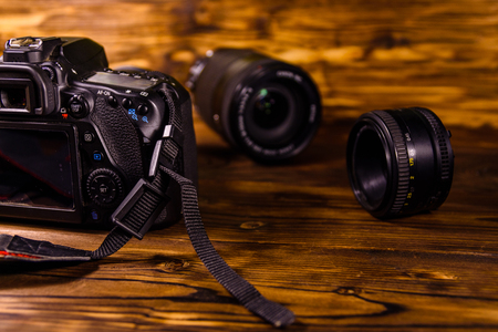 Modern dslr camera and lenses on rustic wooden table