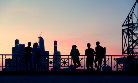 Silhouettes of young people watching the moscow cityscape from the observation deck by a summer evening with a blue and red sky as a background Stock Photo