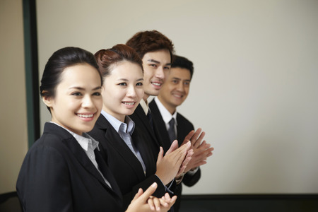 Business people standing in a row clapping their hands Stock Photo