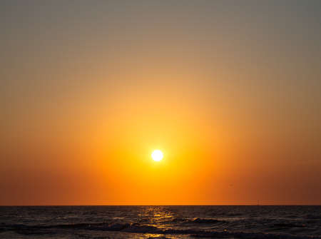 Atardecer romántico junto al mar. El sol poniente sobre las olas.