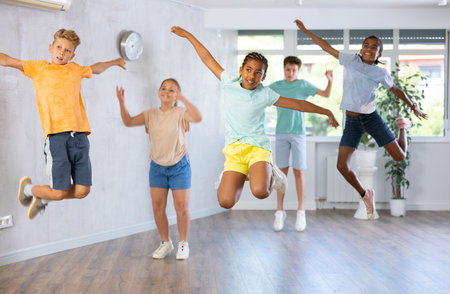 Grupo de chicos y chicas juveniles positivos saltando alegremente en el dancehall