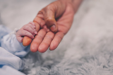 Grandmother hand holding newborn baby grandson finger