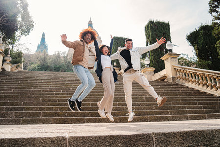 Group of multiracial happy friends having fun jumping on the street spreading arms three multicultural teenage students leaping and laughing together diverse people hanging out